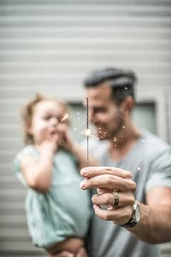 Man with daughter in backyard with sparkler