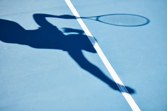 Shadow on Tennis Court of Woman Serving