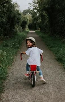139763 Young Girl on Bike Down a Lush Path USP Crop